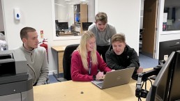 Group of graduates sitting around laptop