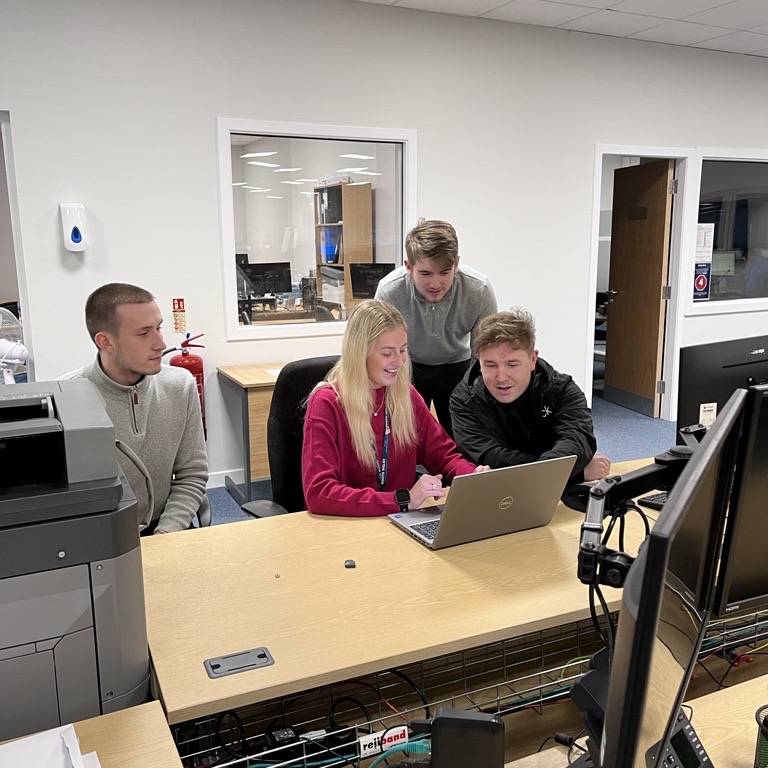 Group of graduates sitting around laptop